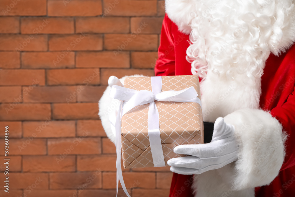 Santa Claus with gift on brick background, closeup