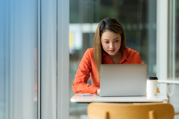 Beautiful young woman using laptop sitting on a coffee shop