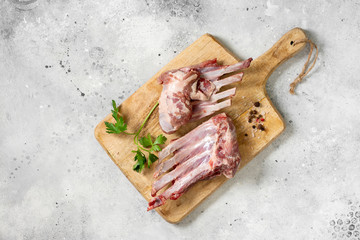 Wall Mural - Raw ribs of a young lamb. Raw lamb ribs in a black ceramic plate on the black kitchen table. Raw meat of a young lamb on the table	