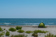 green tent installed on remote wild beach. Enjoy a vacation on the sea side while maintaining social distance.