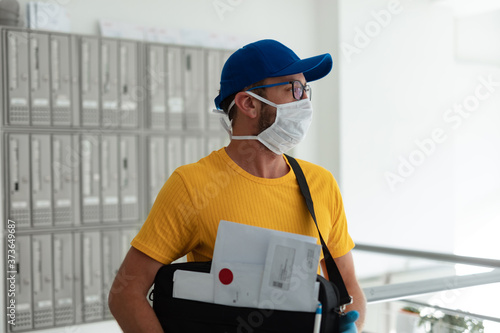 Mailman delivering mail with mail-bag and protective mask and gloves during virus pandemic.