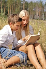 girl and boy in nature schoolchildren read a book in nature