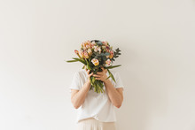 Young Pretty Woman In White Blouse Holding Tulip Flowers Bouquet In Hands Against White Wall. Holiday Celebration Festive Floral Concept