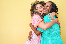 Happy Mother And Daughter Hugging Each Others With Yellow Wall In Background - Family People, Motherhood And Love Concept