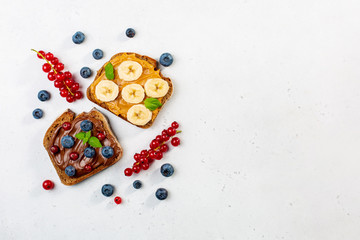 Sticker - Sweet sandwiches with peanut butter and chocolate butter decorated with bananas, berries, mint. Copy space.