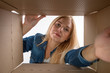 © Plutmaverick - Young beautiful girl blonde, opens and peeks into a cardboard box. To get or to put things to move, bottom view.