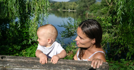 A lovely mother and a cute baby on a bench at a nice lake