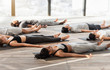 © Prostock-studio - Group of sporty people relaxing during yoga lesson, lying in Corpse pose