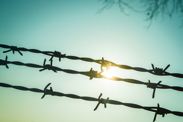 Barbed wire on fence with blue sky to feel worrying