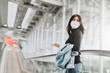 Asian woman tourist wearing face mask holding passport on escalator at airport terminal during coronavirus or covid-19 outbreak . New normal travel at airport