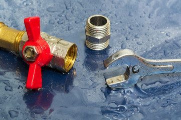 Plumbing faucet and a wrench in water drops during equipment repair during an accident