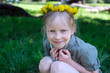 Little blonde smiling girl with a dandelion wreath on head