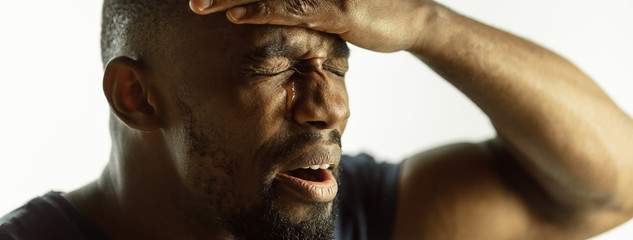 Wall Mural - Crying. African-american young man's close up shot on studio background, flyer. Concept of human emotions, facial expression, sales, ad. Copyspace. Beautiful male model with bright expression.