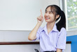 © NONTANUN - portrait of young girl in a Thai high school student wearing braces pointing forward. Copy space