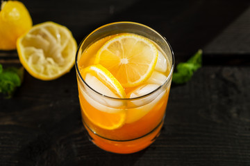 Citrus lemon iced tea close up on dark background. A refreshing summer drink made of fresh hand squeezed lemon mixed with cold black tea, ice and sugar. Add orange juice & alcohol for a cool cocktail.