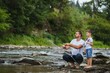 © Serhii - A father teaching his son how to fish on a river outside in summer sunshine