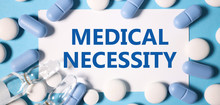 medical necessity. text on white paper in blue letters on a blue background near different pills and ampoules medetsin concept