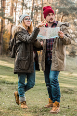 Wall Mural - Traveler couple with map, compass and backpack exploring forest. Freedom and active travel concept.