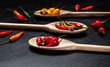 © BY BRAZIL - Various types of peppers in wooden spoons on a black background. Top view.