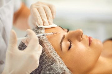 Wall Mural - Cosmetologist making facial beauty injection to young woman in beauty salon