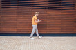 © BullRun - Male watching smartphone while walking against city wall