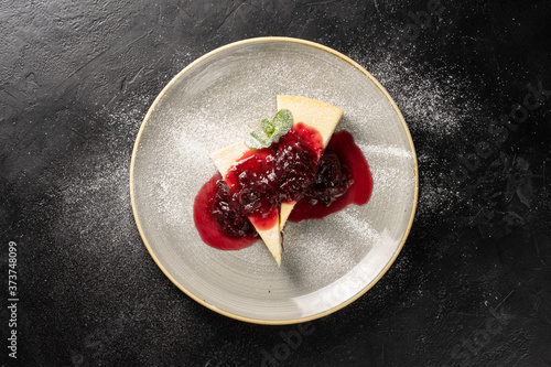 Two pieces of cheesecake on a round plate drizzled with strawberry jam and garni Tableau sur Toile