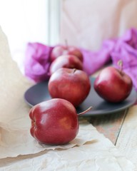 Red fresh apples on a plate, bright cloth on a wooden table, healthy food concept, organic fruits, autumn season, at home