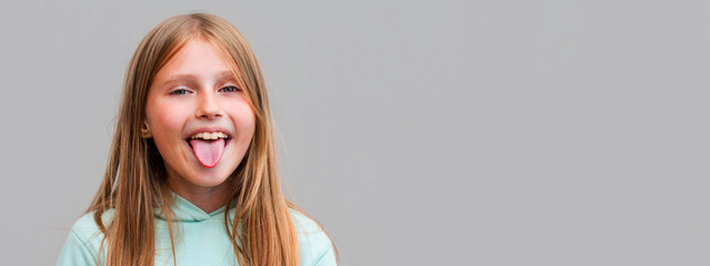 Funny cute young girl smiling winking showing tongue looking at camera over gray background.