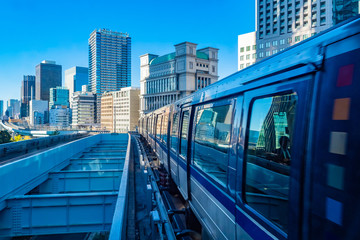 Wall Mural - Transport Of Japan. Movement of the train in the center of Tokyo. The train goes near office buildings. Transport infrastructure of the Japanese city. Urban landscape in blue tones. Urbanistics.