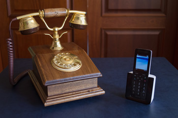 Wall Mural - High angle shot of a vintage telephone and a modern cellphone on a blue surface