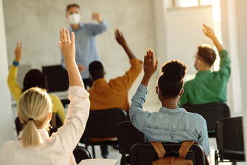 Canvas Print - Back view of group of students raising their arms during a class at lecture hall.