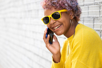 Wall Mural - afro american girl with mobile phone in the street and sunglasses