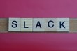 text the word slack from gray wooden small letters with black font on an red table