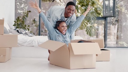 Wall Mural - A loving couple has moved in a new dwelling. The African-American boyfriend and girlfriend are having fun and playing with packages. The concept of relocation.