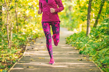 Wall Mural - Run in forest at fall. Fit woman running in nature outdoors doing fitness workout in autumn park. Girl athlete jogging outdoor.