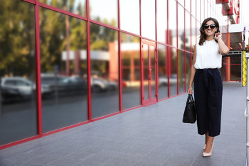 Young businesswoman near modern building on city street