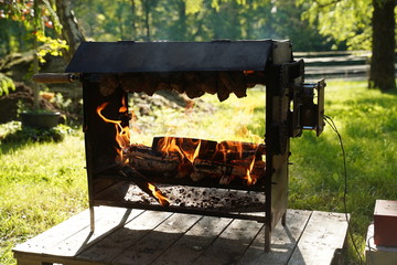 2 trussed chickens roasting over an open log fire