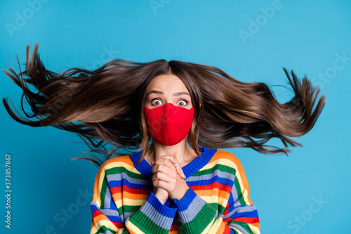 Photo of shocked crazy girl ask stop quarantine covid infection put hands together her haircut fly air wear medical mask jumper isolated over blue color background