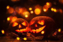 Halloween Pumpkin Head Jack O Lantern With Burning Fire Background, Wooden Table  With Light Bokeh Garland. Beautiful Holiday Autumn Composition