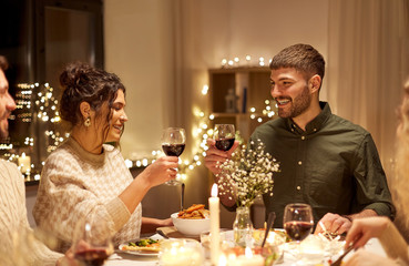 Wall Mural - holidays, celebration and people concept - happy friends having christmas dinner at home drinking non-alcoholic red wine