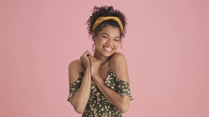 Wall Mural - A pleased african american young woman is getting compliments standing isolated over pink background