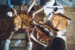 © BullRun - People together grabbing slices of pizza from box at table