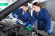 Young female master with foreman are replacing the oil in the car in a workshop