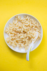 Sticker - boiled pasta on child plate with spoon on yellow background