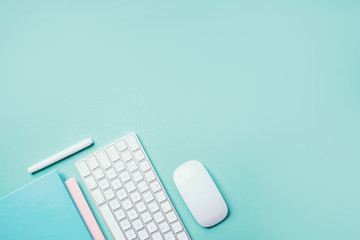 White mouse, keyboard, notebook, pen on blue background. Top view. Copy space. Flat lay. Remote job, work. Home office workspace. Feminine workspace. Blogger, business concept. Mock up