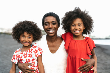 happy african family having fun on the beach during summer holidays - portrait of afro people enjoyi