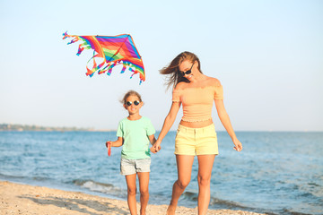 Poster - Woman and her little daughter flying kite on sea beach at resort