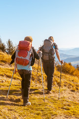 Two old people with large backpacks to hike through the autumn mountains,  concept of active recreation in old age