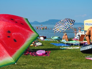 Balatonmáriafürdő, Hungary - July 29, 2020: Colorful umbrellas, sunbathing and bathing people on the beach of the lake Balaton, Hungary in hot July day