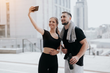 Wall Mural - young couple handsome brunette man and beautiful woman in sportswear doing selfie on smartphone during street workout, healthy fit lifestyle